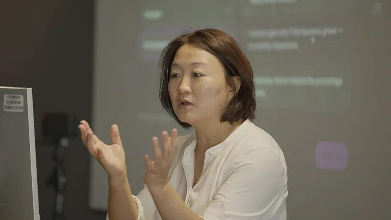A presenter explaining a point in front of a projected learning scenario.